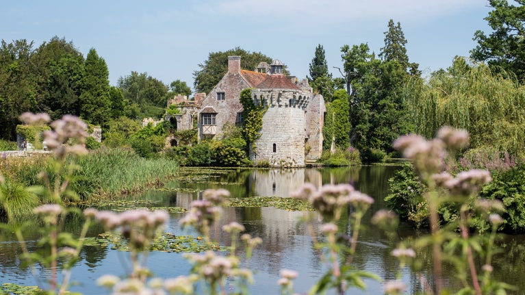 A view across the moat towards the old castle with flowers in the foreground
